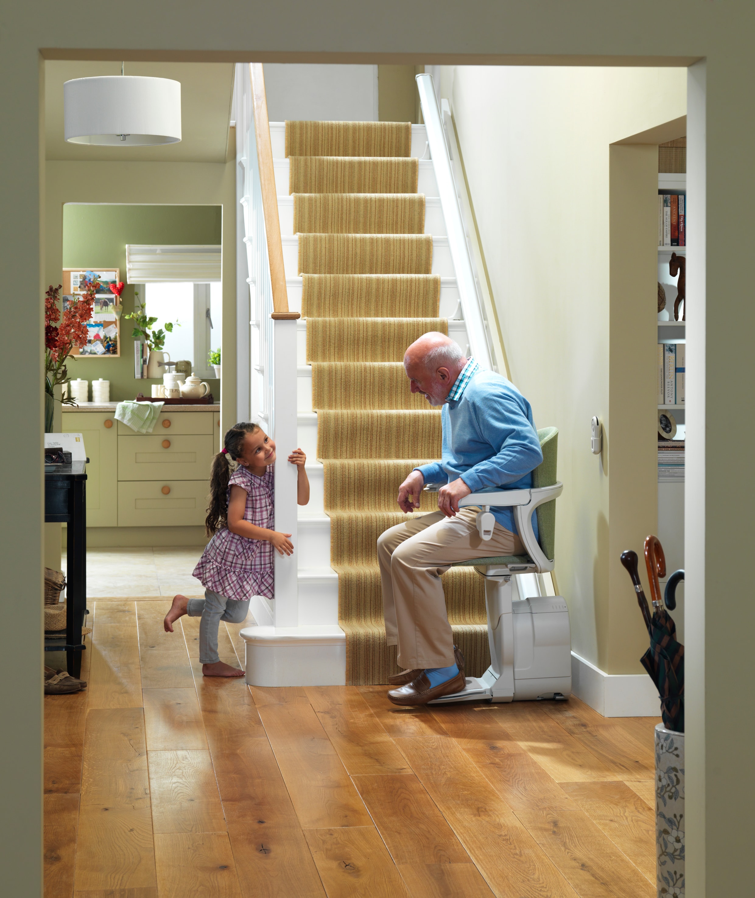 Grandfather using stairlift with granddaughter at home